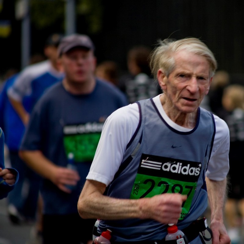 older man running wearing a race bib