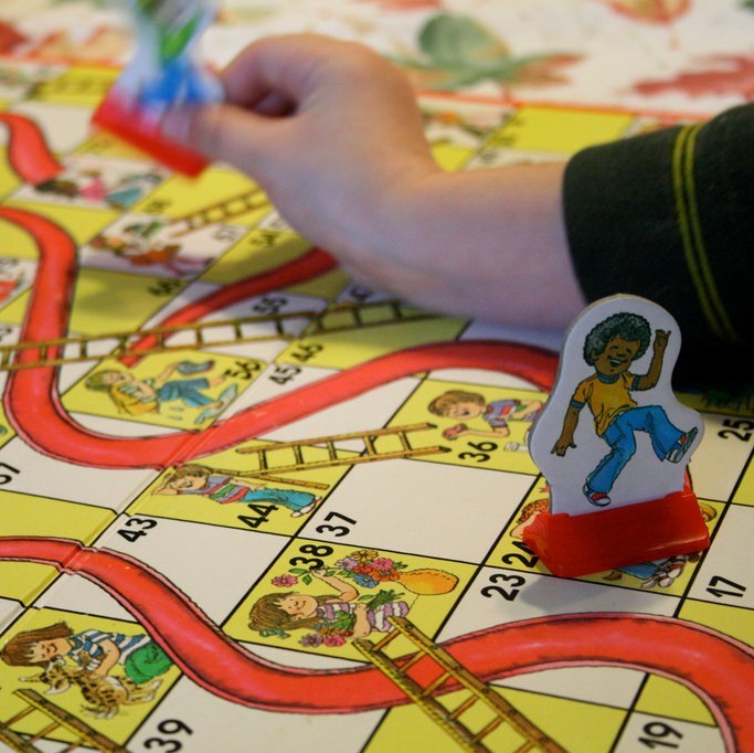 photo of a small child's hand playing snakes and ladders