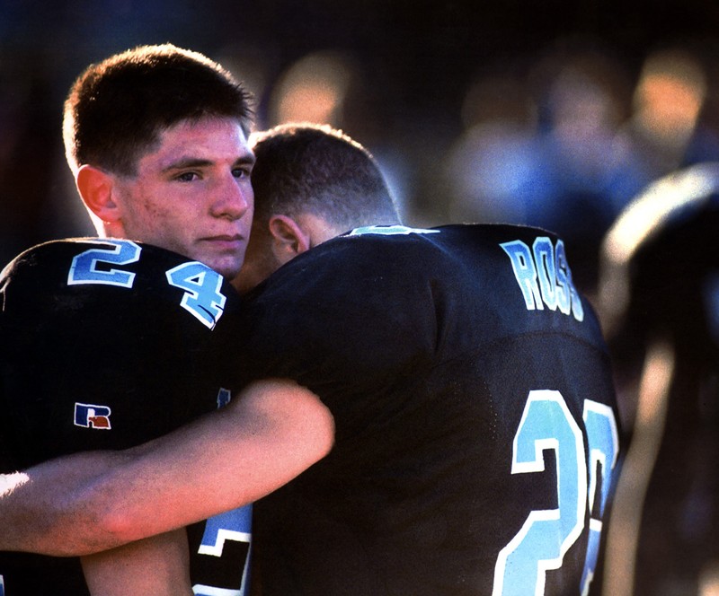 photo of two men in football gear hugging