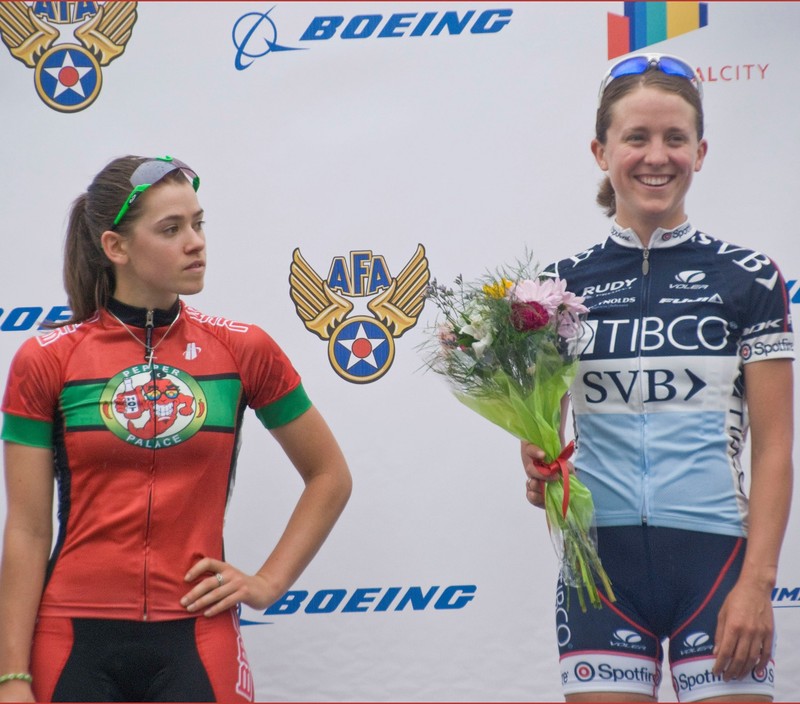 photo of two woman on podium after a porting event, one is smiling and holding flowers the other is straight faced