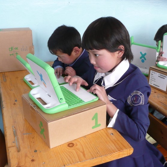 photo of two younger children working on laptops in a classroom