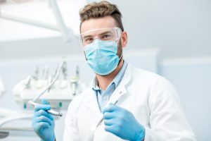 Portrait of a dentist dressed in PPE. Mask and protective glasses during the dental surgery.