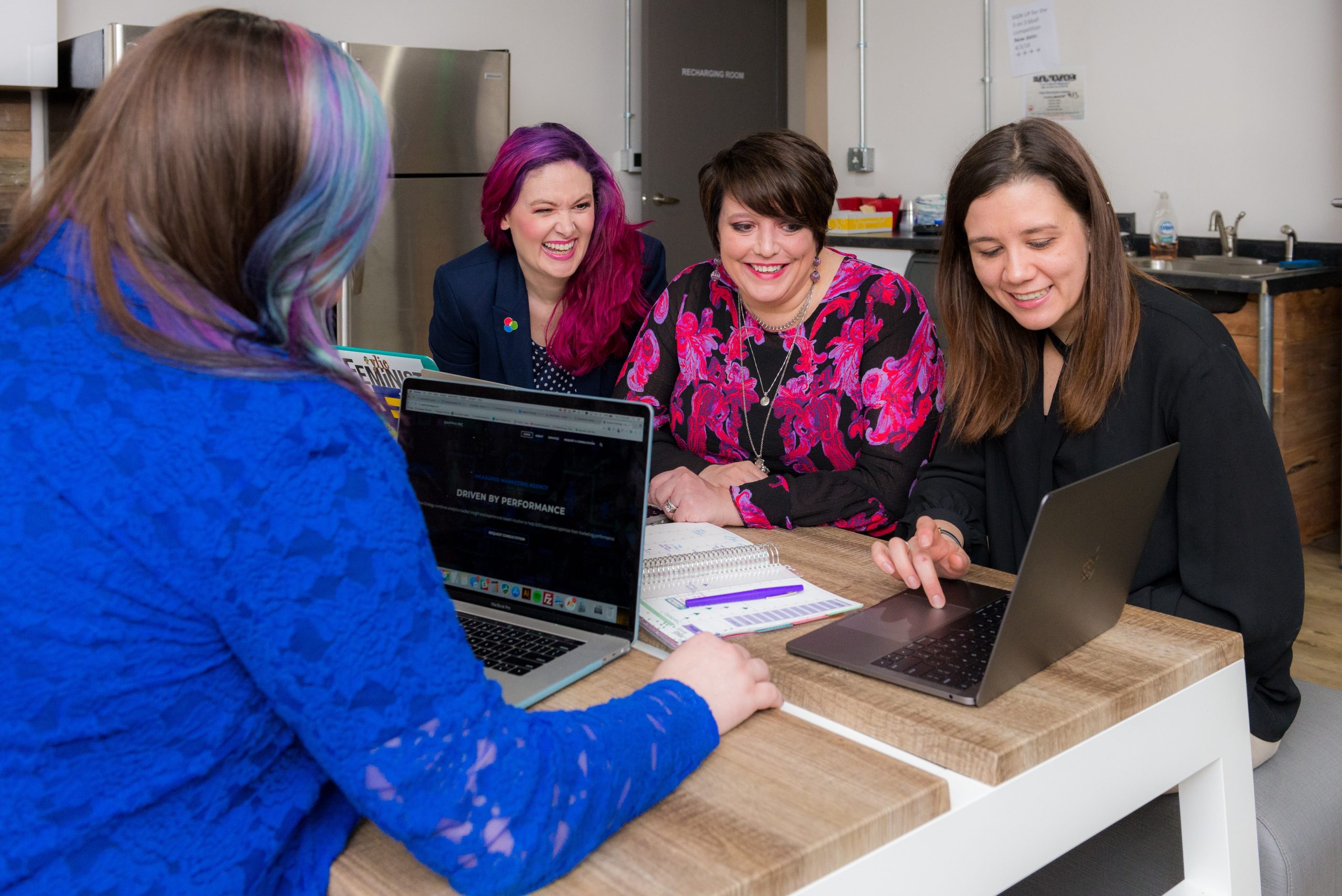 Decorative photograph of four students working together on their laptops.