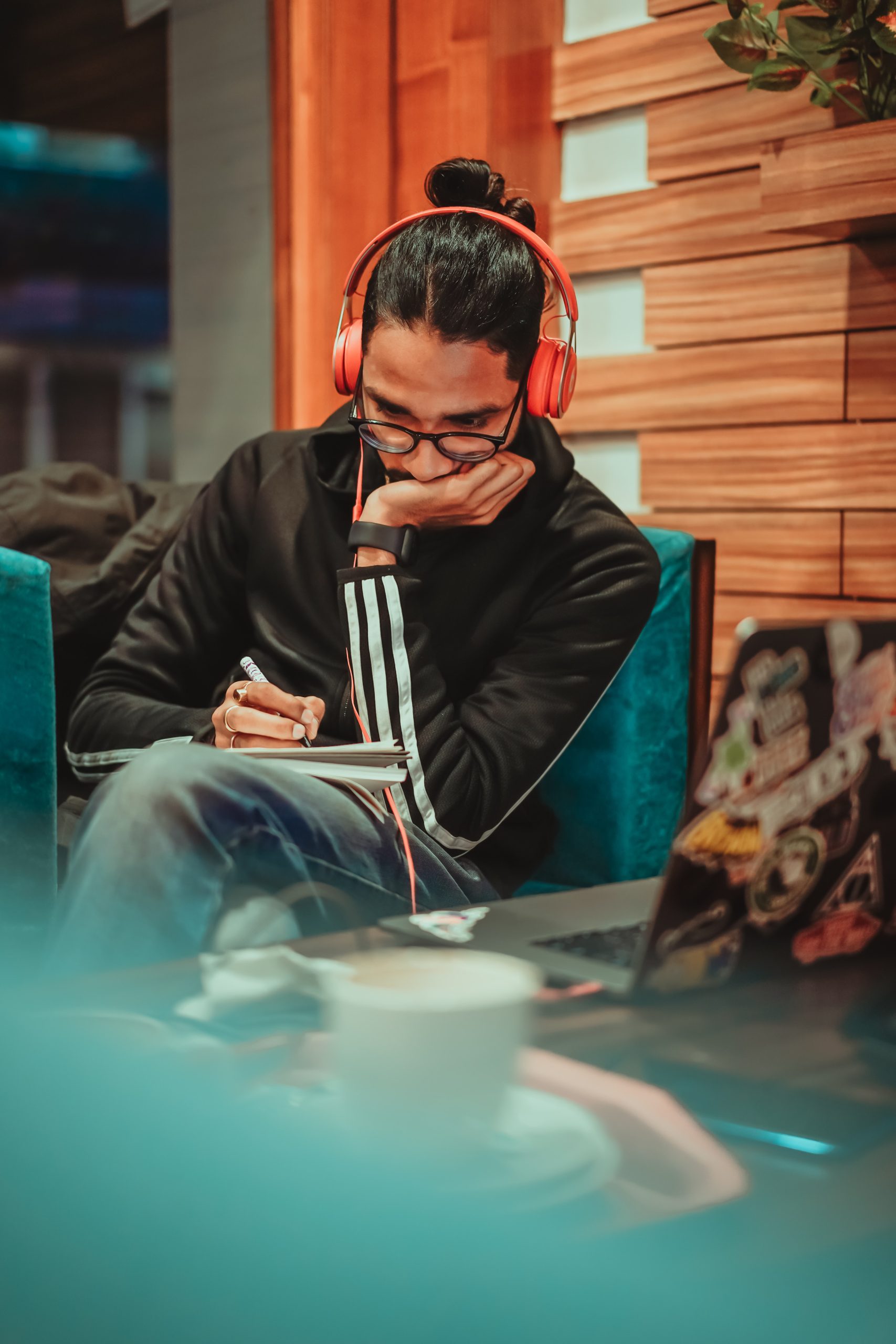 Decorative photograph of a student sitting and completing work in a notebook while listening to music.