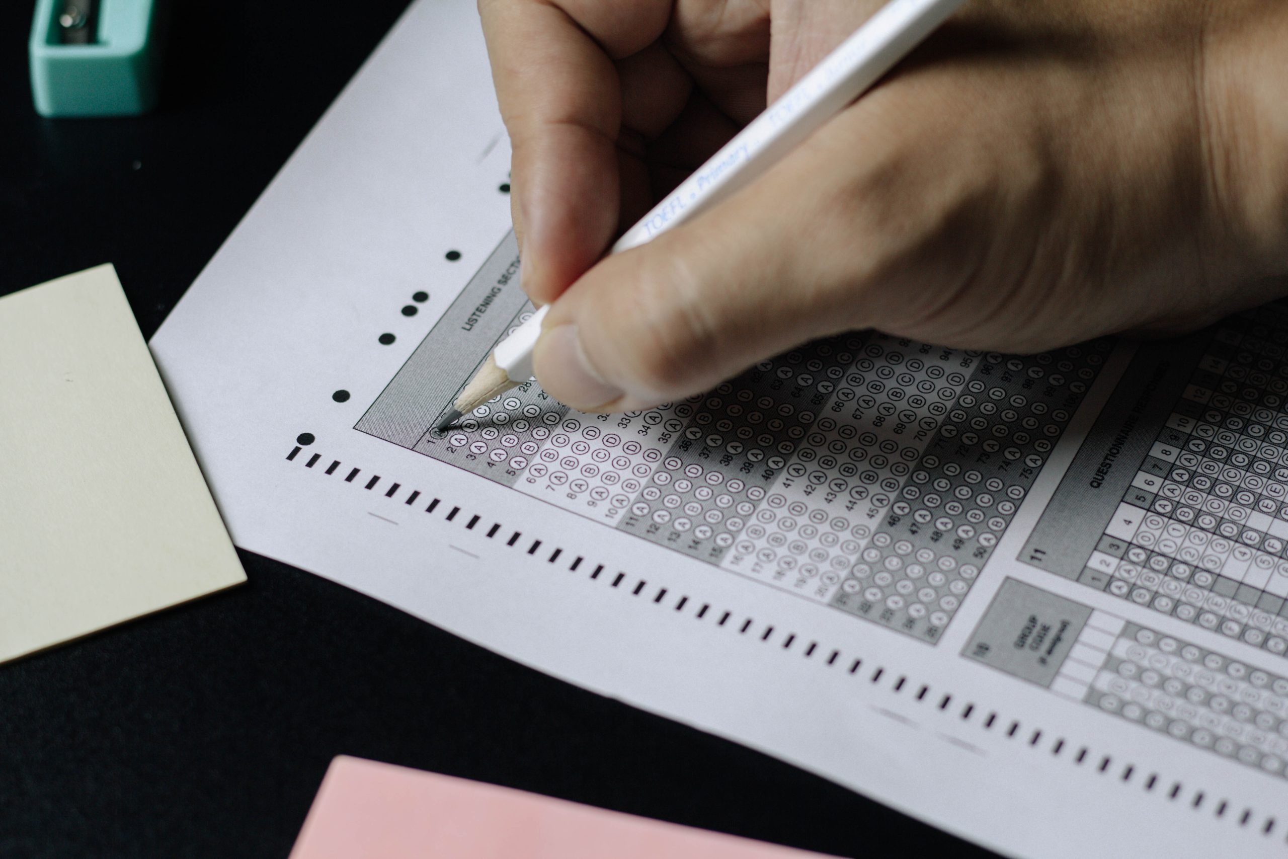 Decorative photograph of a student selecting answers on a scantron exam sheet.