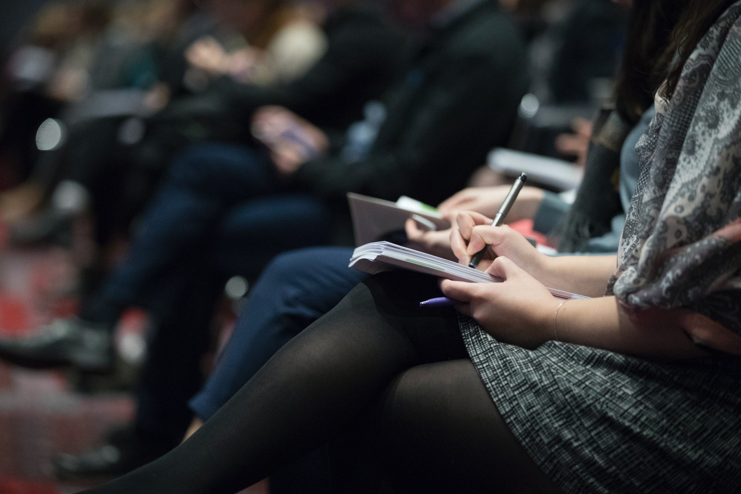 Decorative photograph of students in class taking notes via pen and paper.