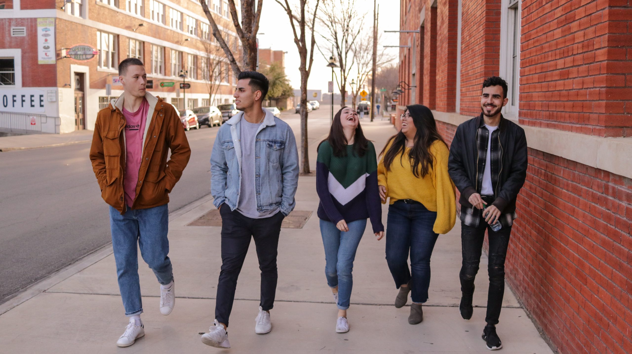 Decorative photograph of five students socializing while walking down the street together.