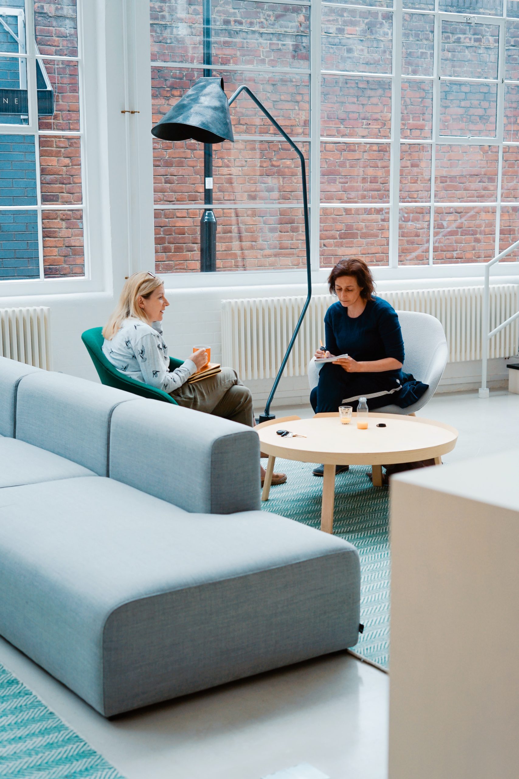 Decorative photograph of two women sitting in chairs across from each other talking.