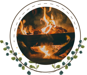 Photo of a burning campfire surrounded by decorative flowers.