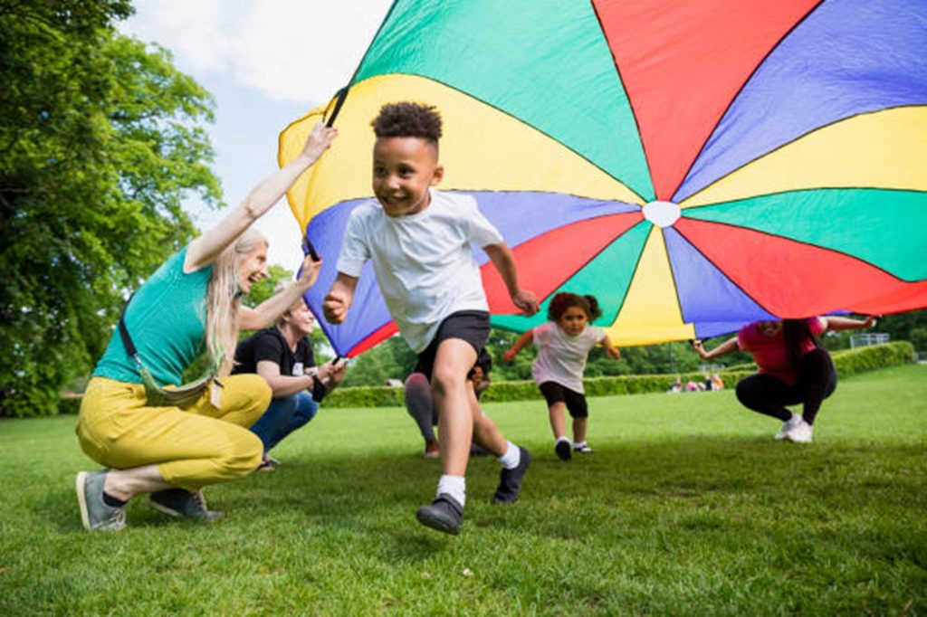 Young children with adult leader playing parachute games.