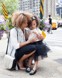 a young girl being held by her mother who is crouching down