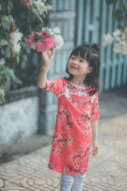 a young girl smelling a flower outdoors