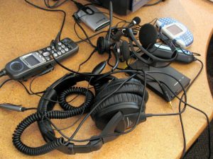 An assortment of teleworking tools are piled on a desk.