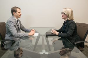 A job interview is being conducted. An applicant is seated across a table from an interviewer.