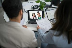 Two employers are conducting a virtual interview through computer video conferencing software