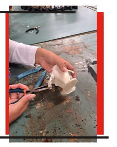 An image of a student cutting a mold from from a 3D printer