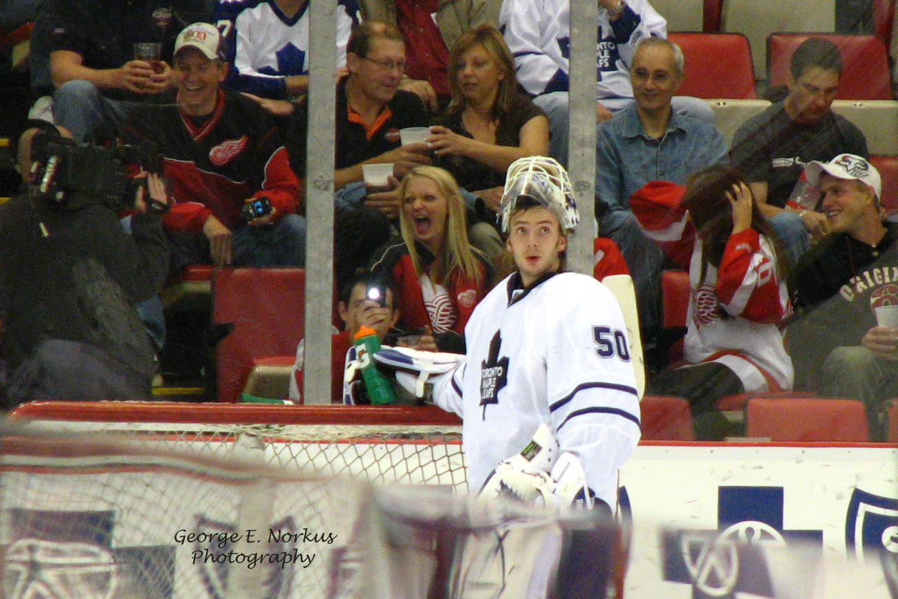 A Toronto Maple Leafs hockey game showing a goalie on the ice and families in the stands, cheering.