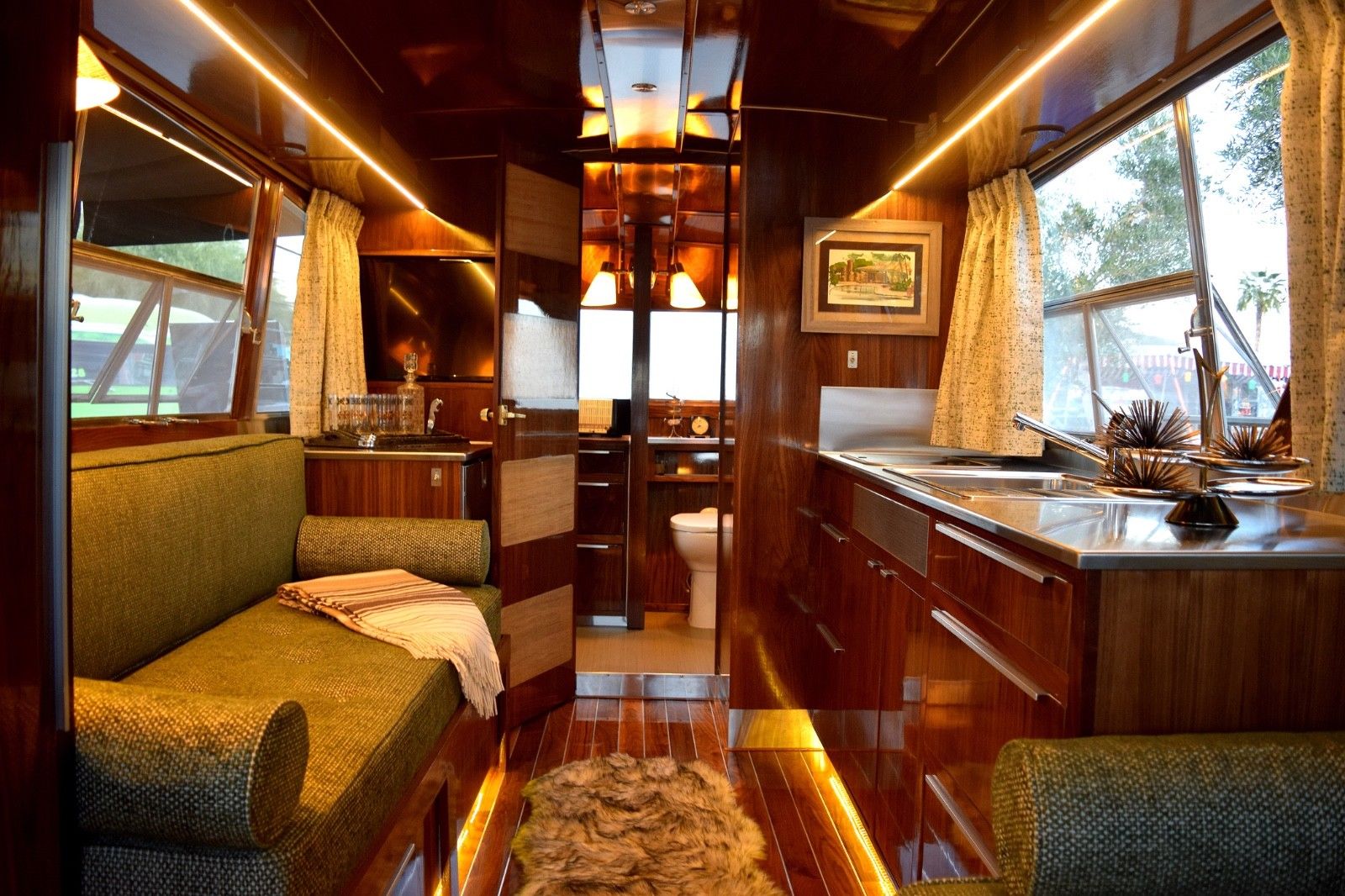 Interior of a trailer, showing a small kitchen with sink, bathroom, and sofa.
