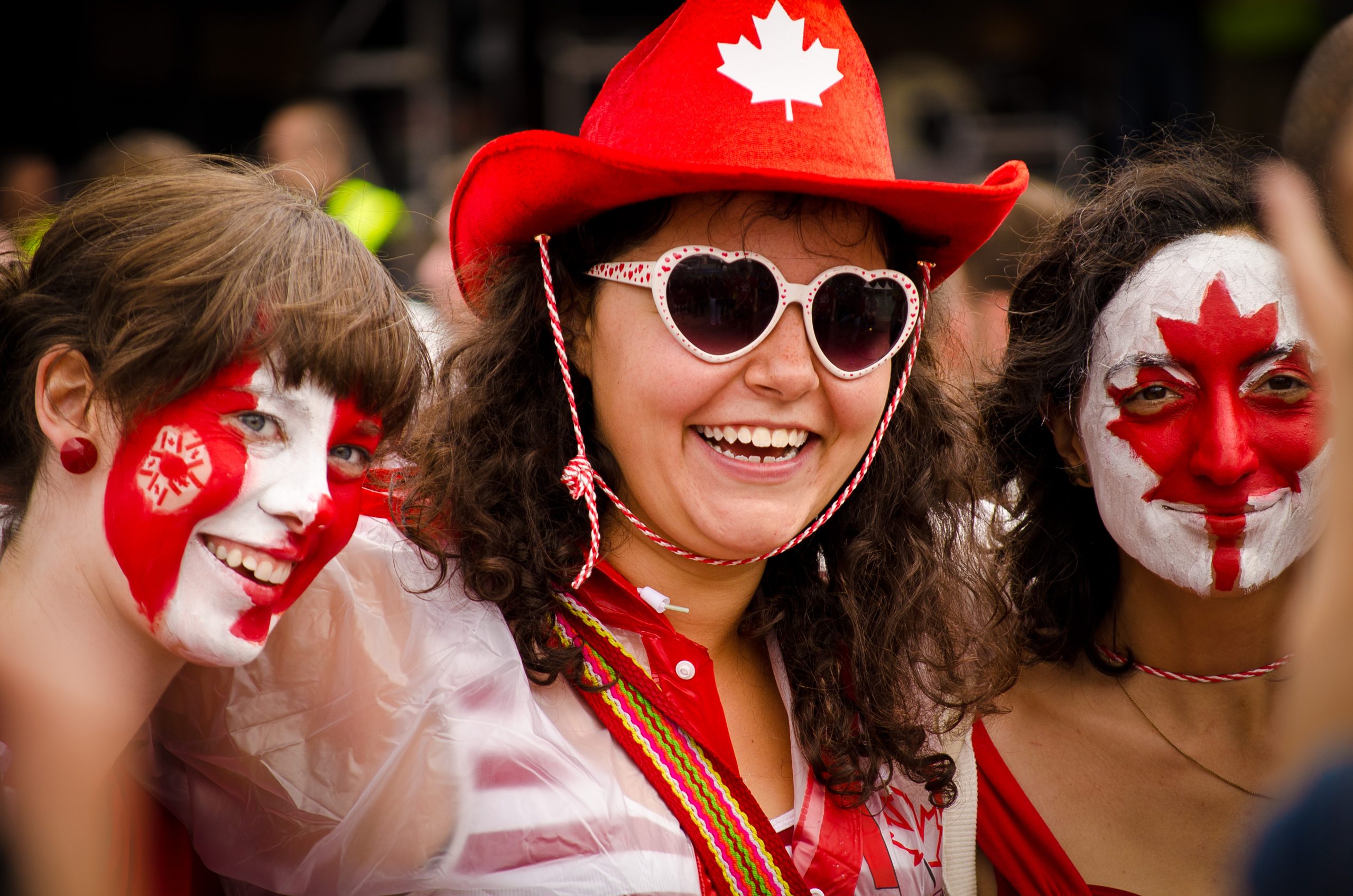 College students at a Canada Day celebration wearing face paint and Canada-themed clothes.