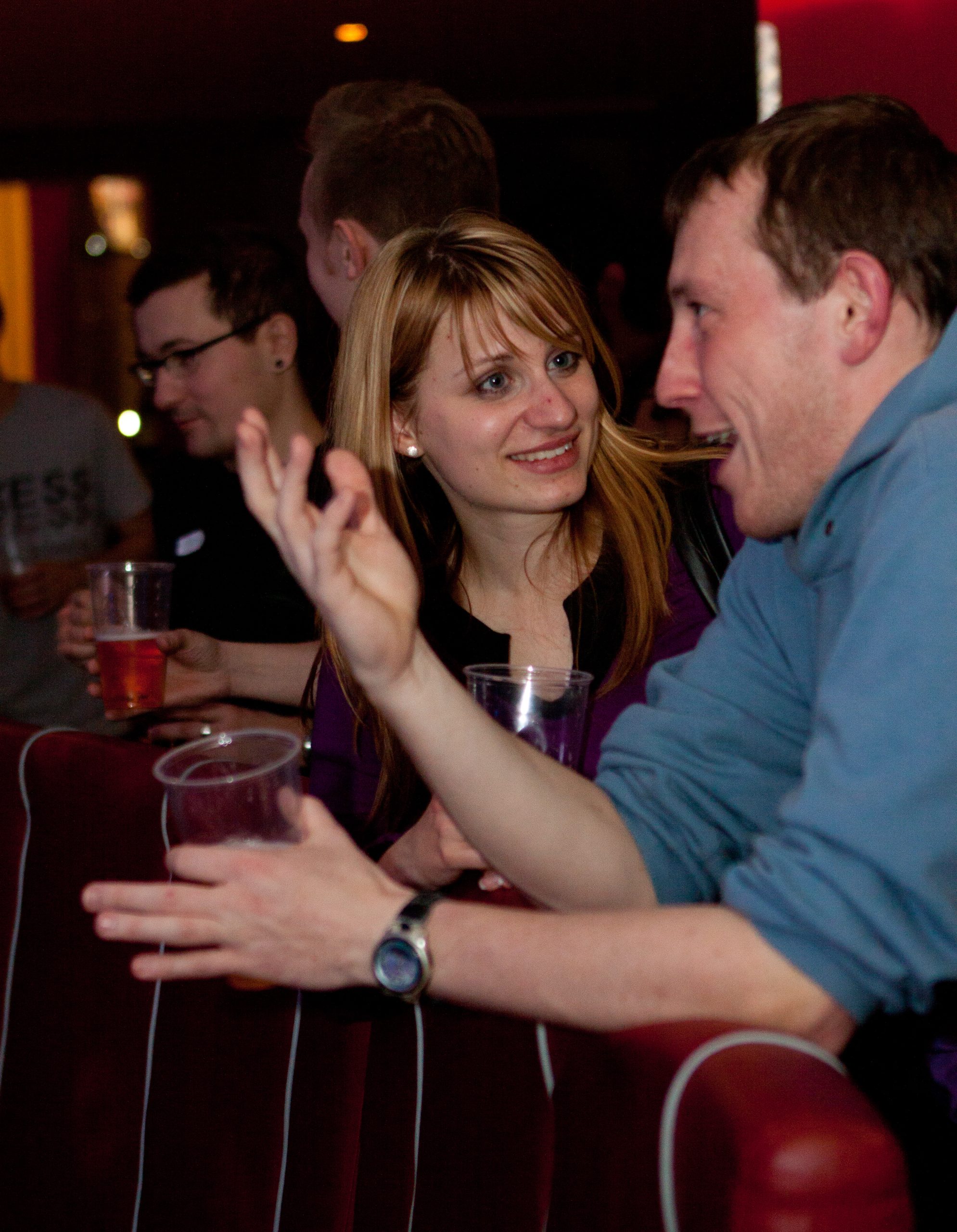 Adults standing at a bar, having a lively conversation.