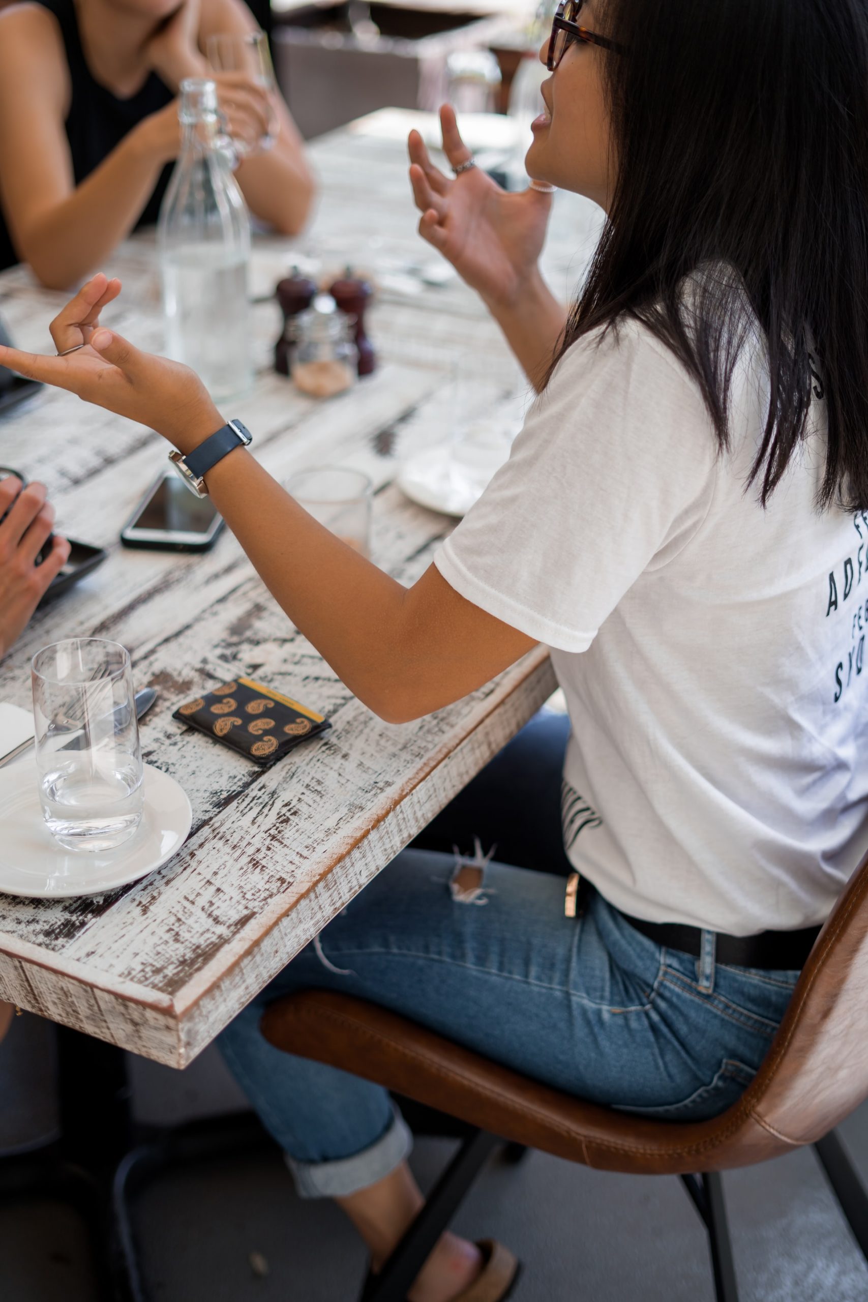 woman with glasses sitting at table talking to others