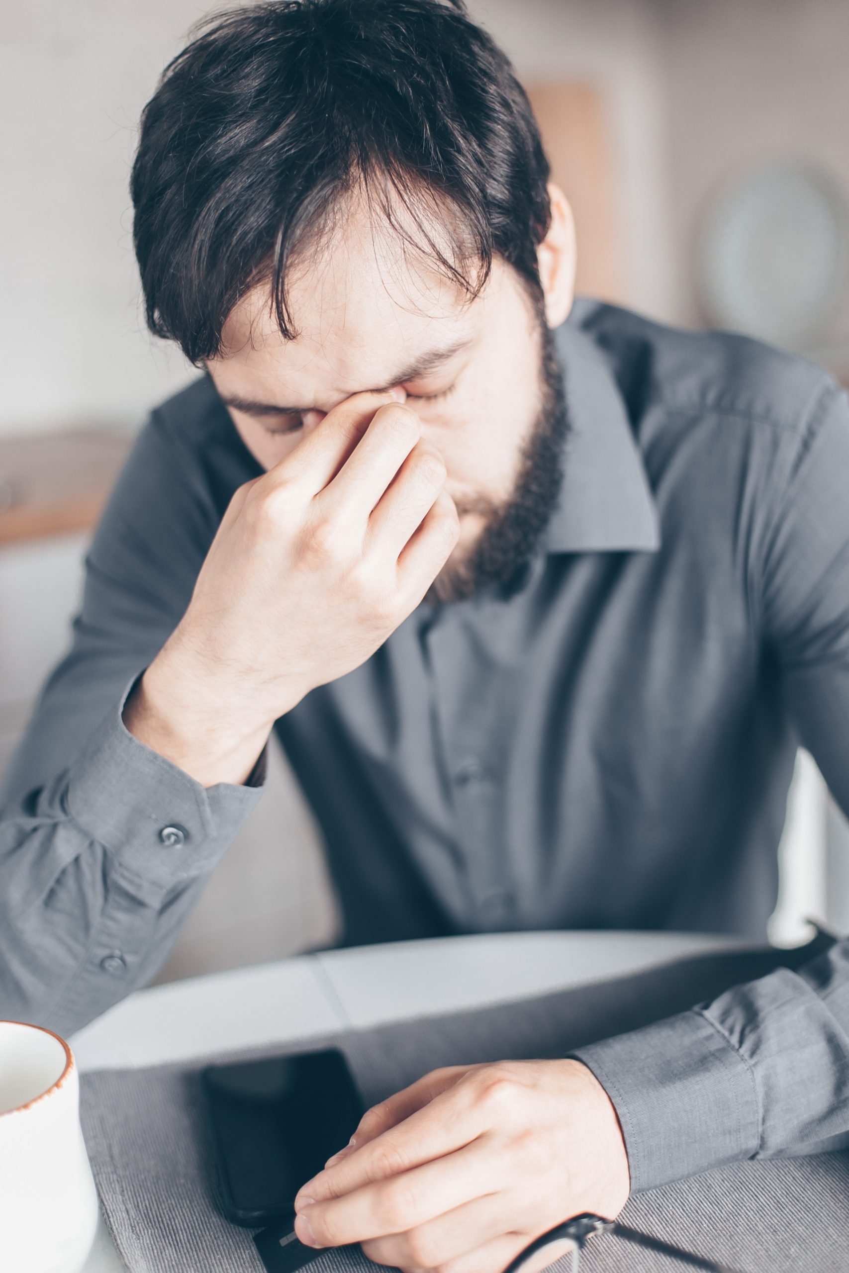 Man wearing dress shirt covering his face.