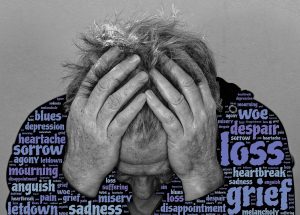 Man with two hands on his head with text for synonyms of sorrow superimposed on his shirt.