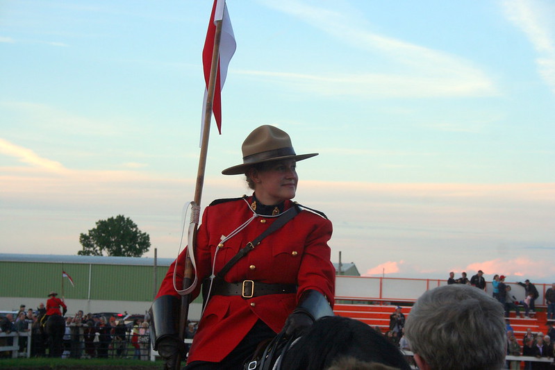 Photo of a Royal Canadian Mounted Police officer holding a flag on horseback.