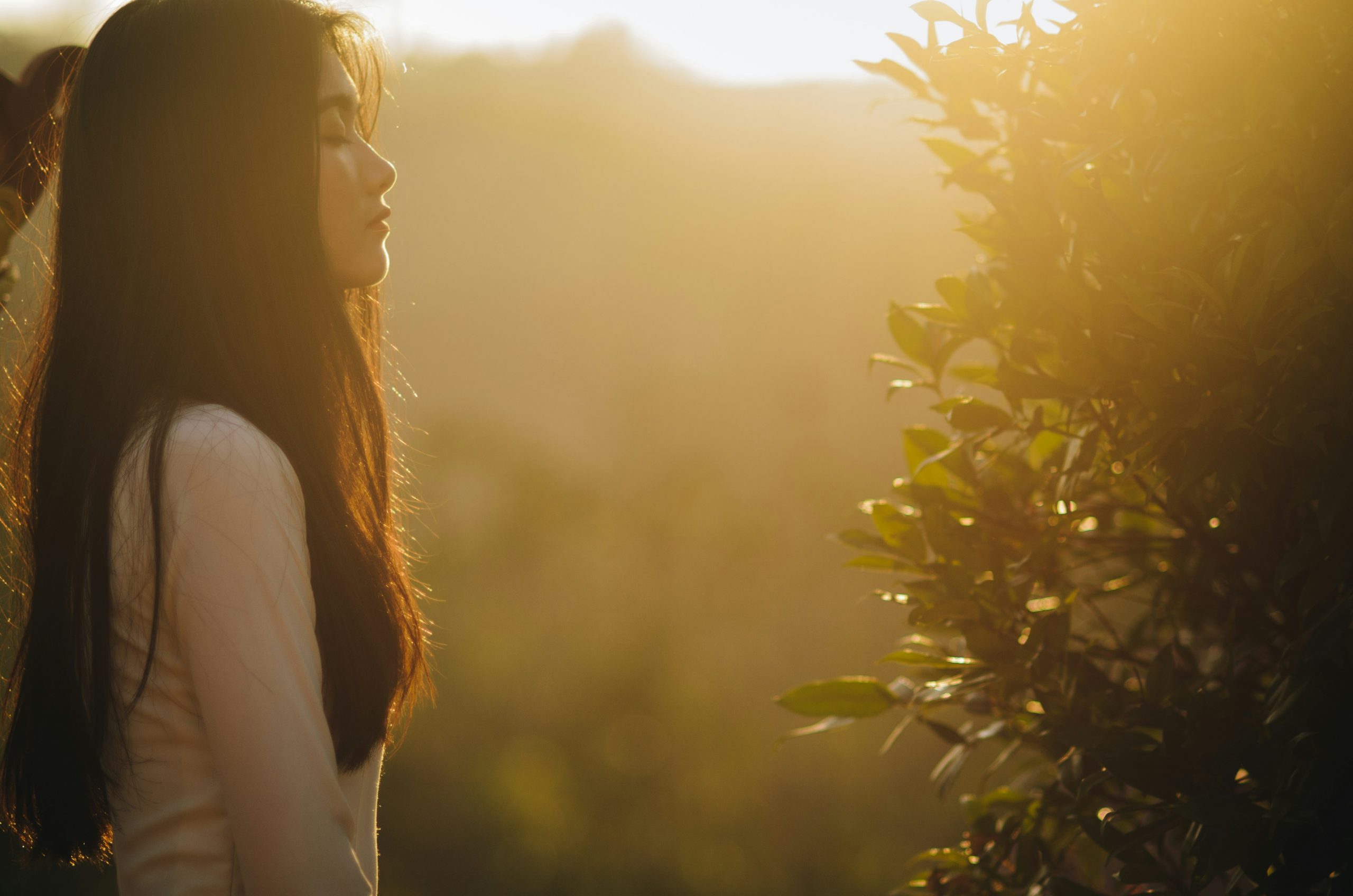 Photo of a woman meditating in nature at sunrise.