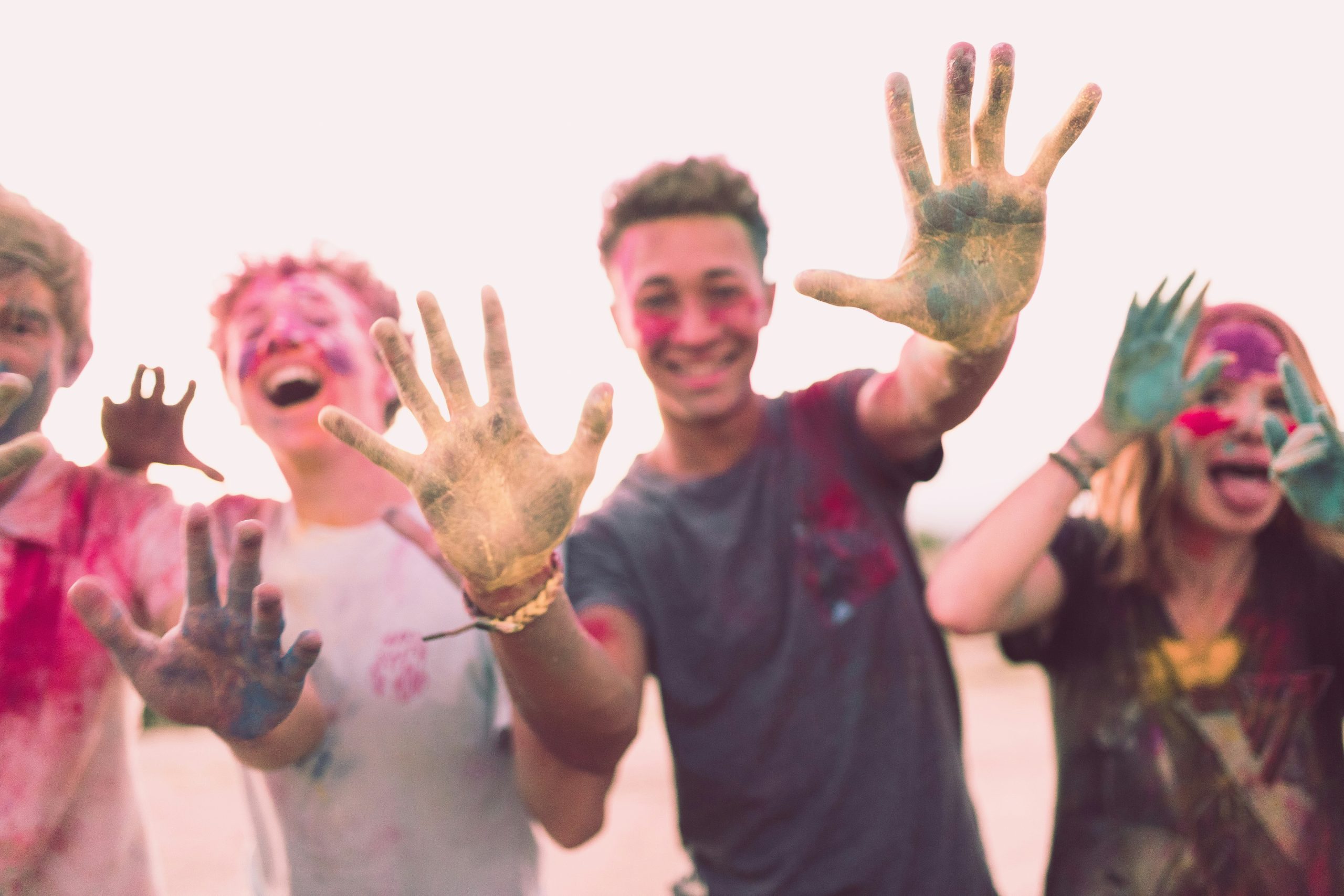 Photo of a group of teenagers with paint-smeared hands and faces.