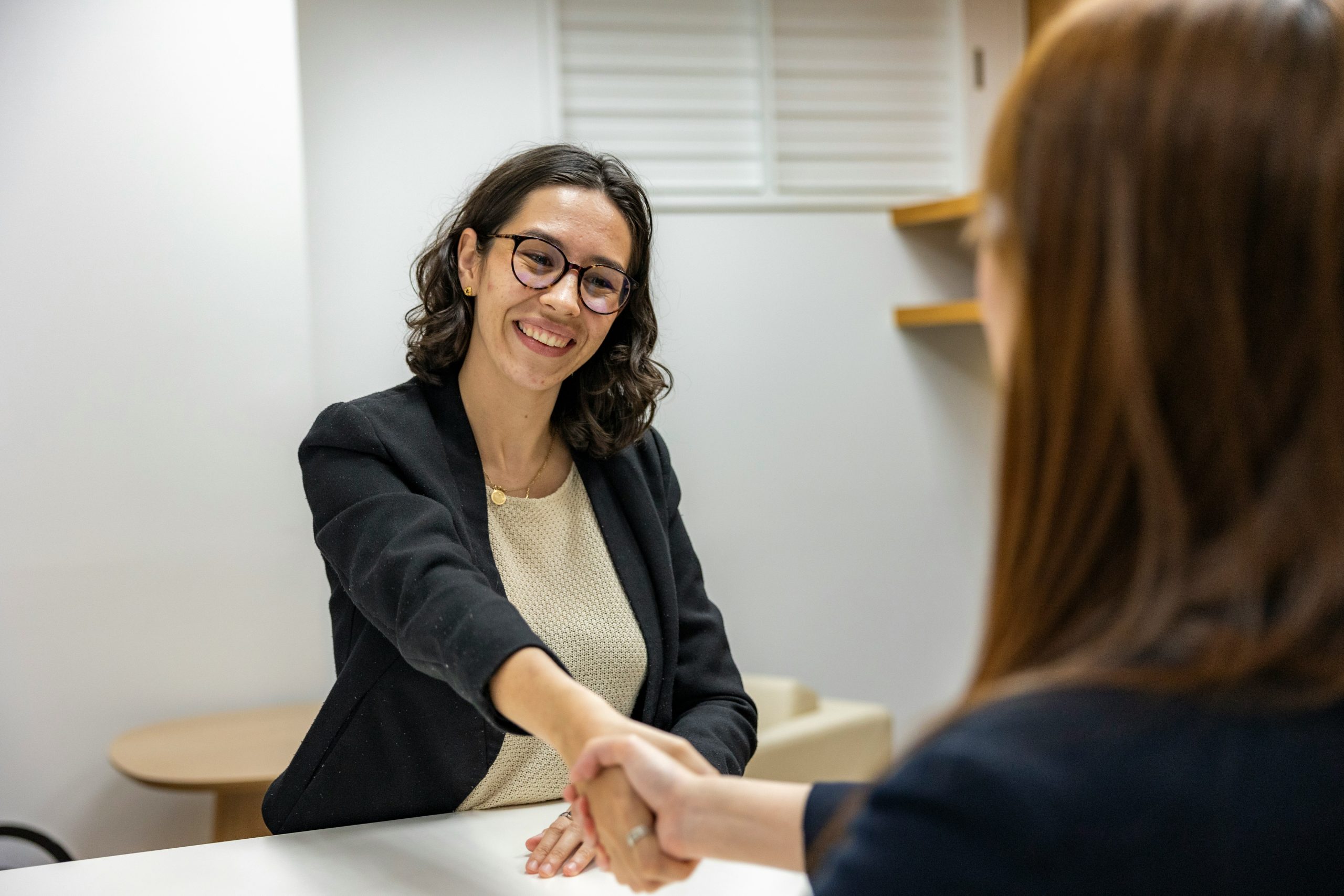 Image of a woman shaking hands with another woman at a table.