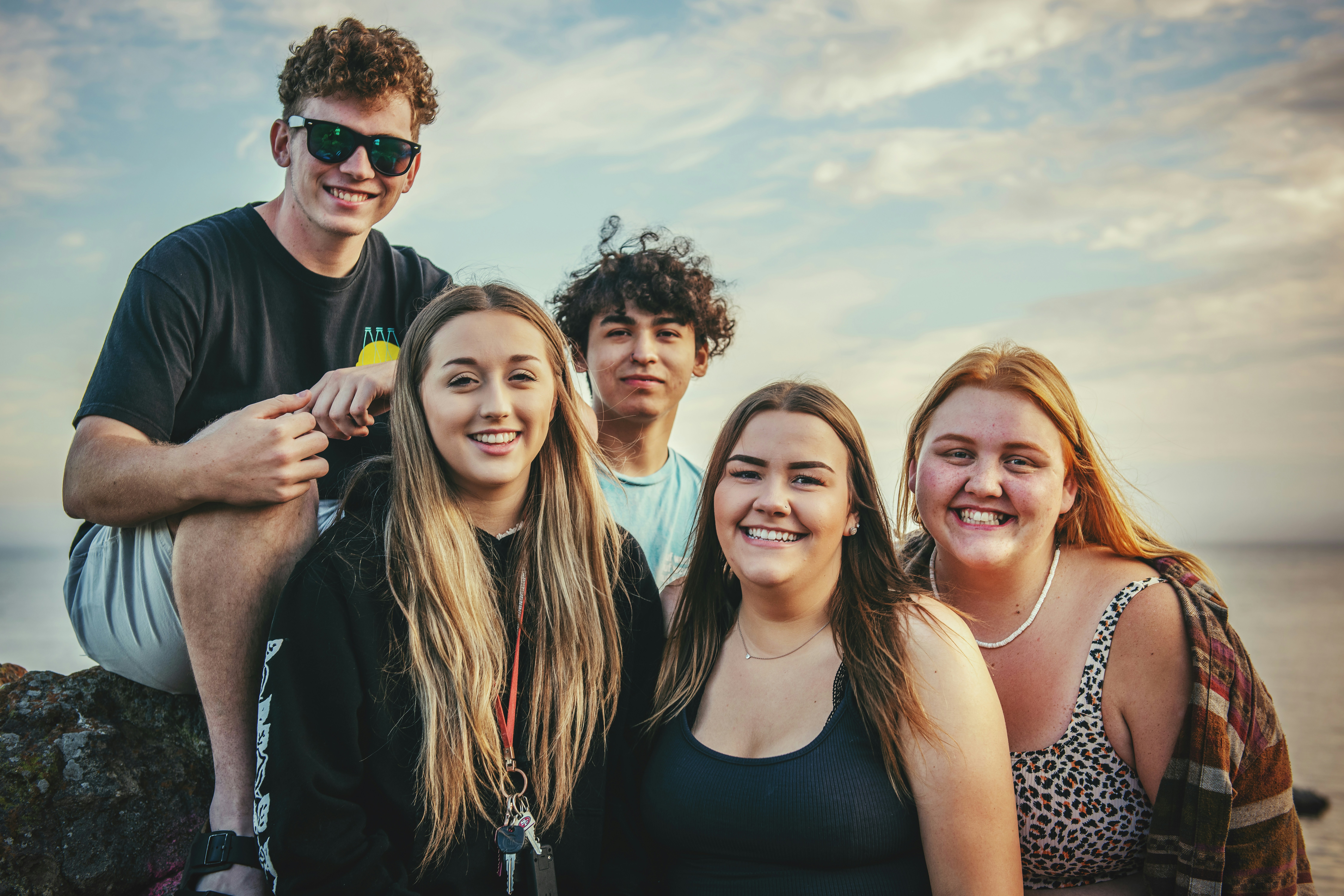 Image of five teenagers standing together at the beach.