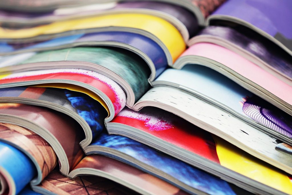Open magazines with colourful images stacked on top of each other.