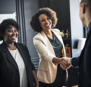 Image of three people greeting each other. Two are shaking hands.