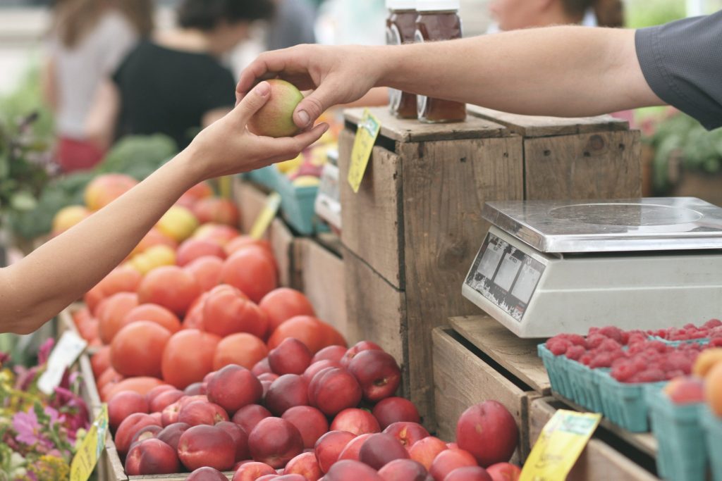 Image of two hands holding an apple at a market