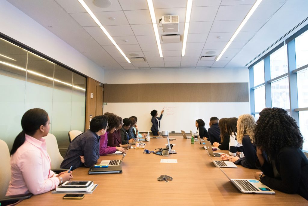 A diverse group of employees attending a presentation in a boardroom.