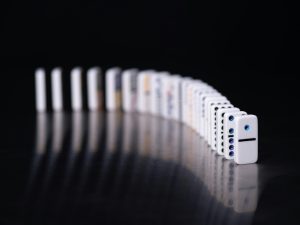 A line of dominoes set to fall, symbolizing the concept of influence as a small initial action that triggers a larger chain reaction.