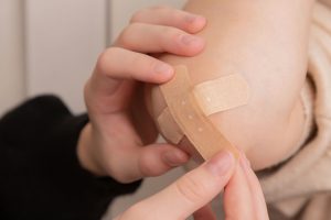 A child's elbow with two band-aids on it.