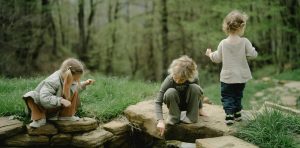 Three children playing outside in water.