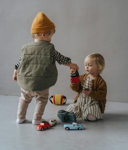 Two toddlers playing together wit toy cars.