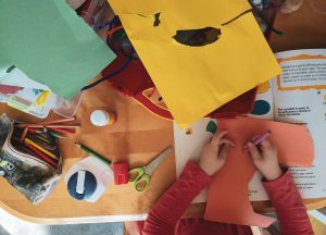 A child drawing on a craft table.