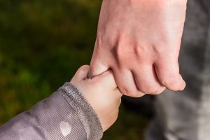 A child holding on to a caregiver's hand.