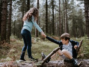 Photo of a girl helping a boy up off the ground