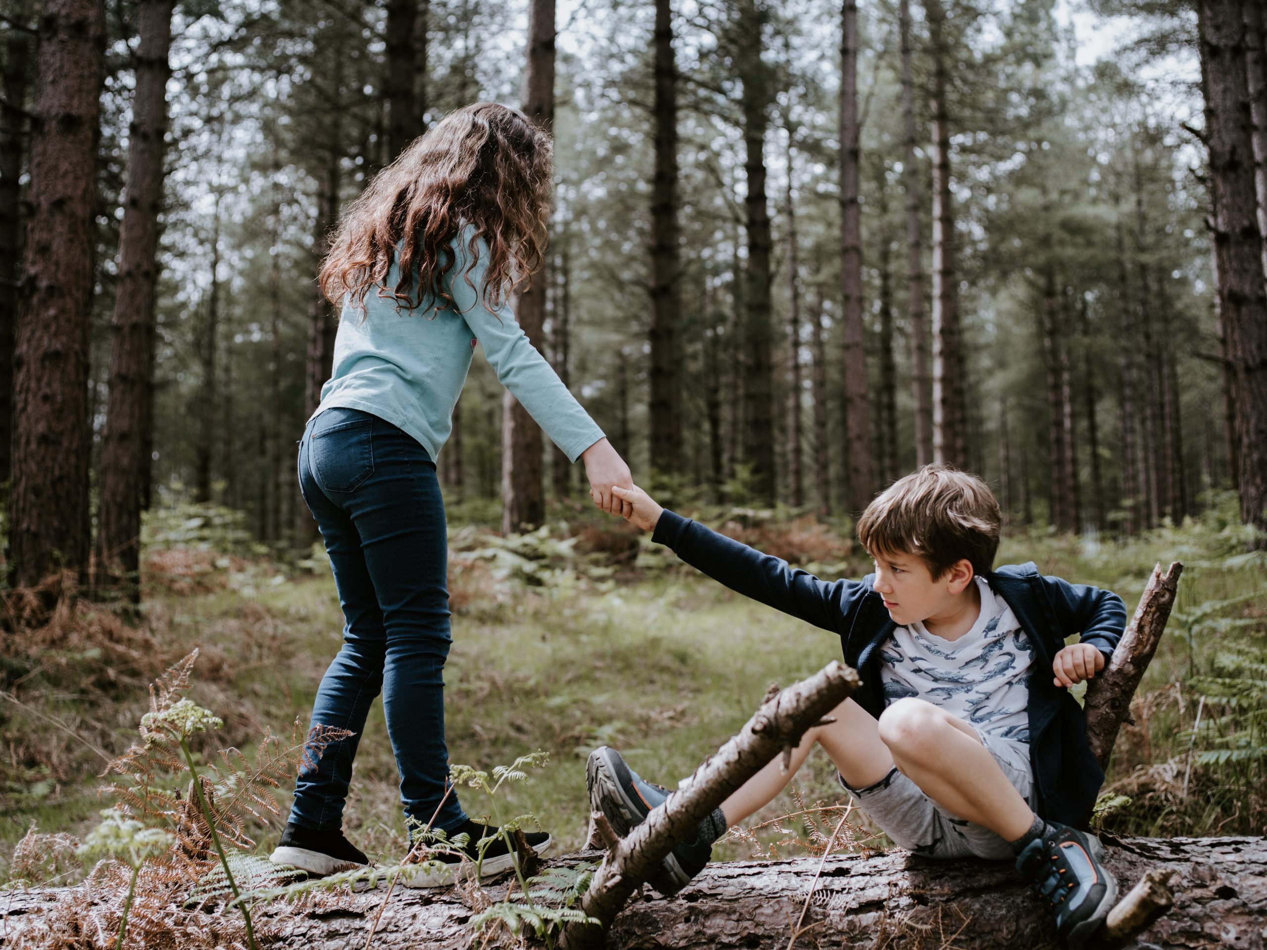 Photo of a girl helping a boy up off the ground