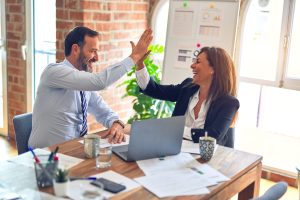 Photo of two middle age business workers smiling happy and confident. Working together with smile on face hand giving high five at the office