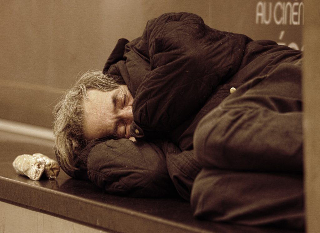 Photo of a homeless man sleeping on a bench in Quebec