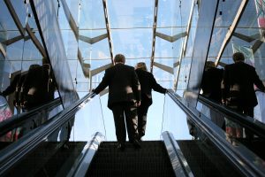 Two people in business attire on an escalator