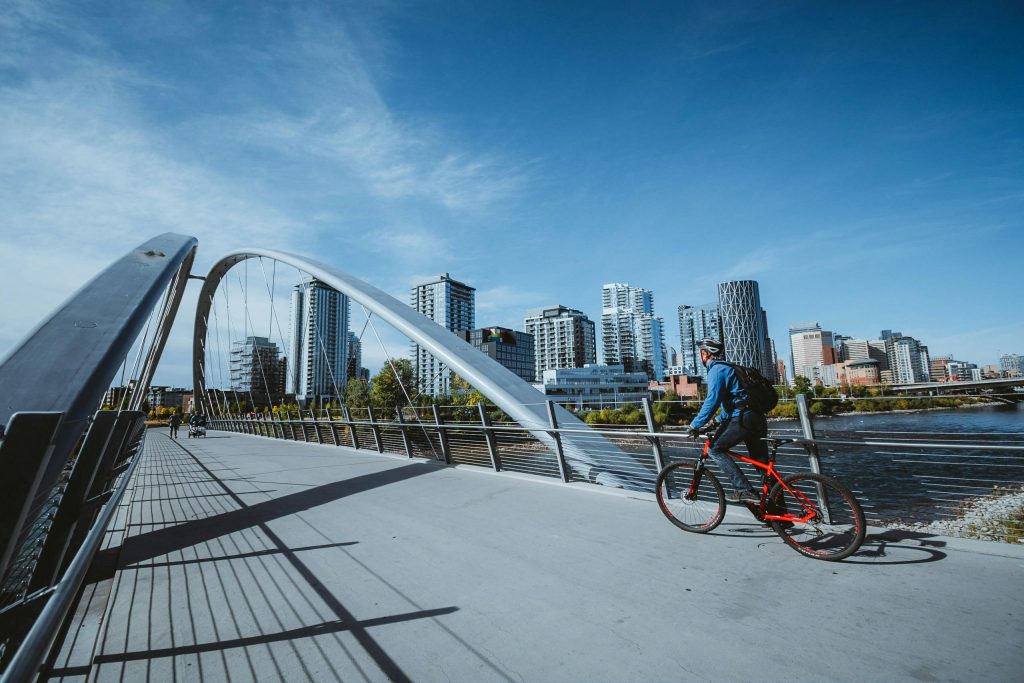 Photo of man riding a bike across a modern bridge