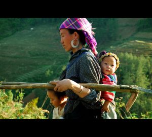 A mother and two children walking home from the farm fields