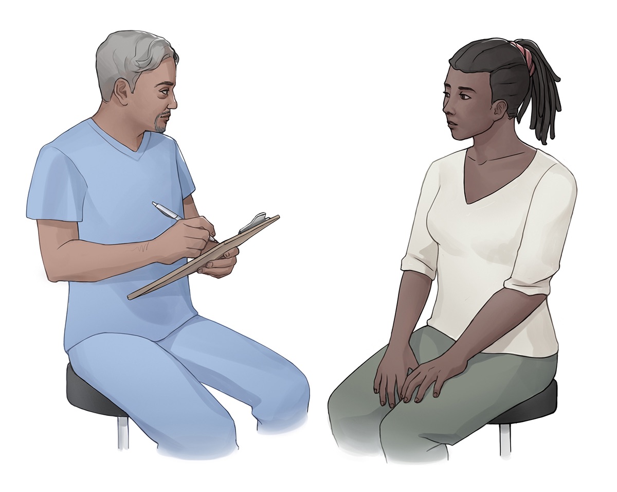 A nurse sitting and holding a clipboard, speaking with a client as they conduct a health assessment.